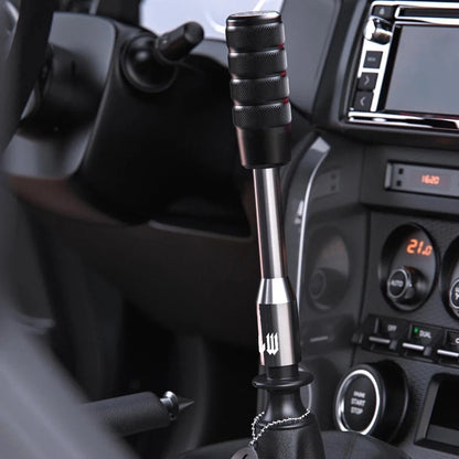 Close-up of a car gear shift lever with a detailed design, set against the interior of a vehicle.
