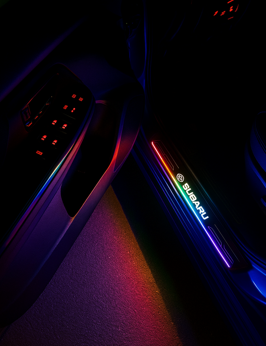 Close-up of a car door with illuminated Subaru logo in a dark setting